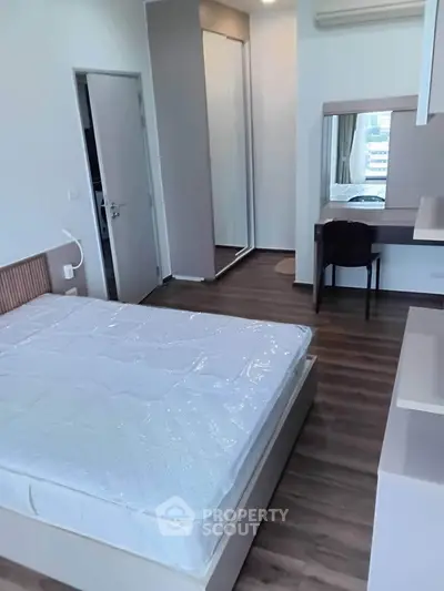 Modern bedroom with sleek design, featuring a comfortable bed, stylish flooring, and a functional workspace.