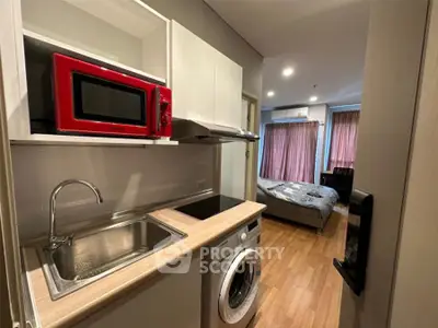 Modern studio apartment with compact kitchen and cozy bedroom area.
