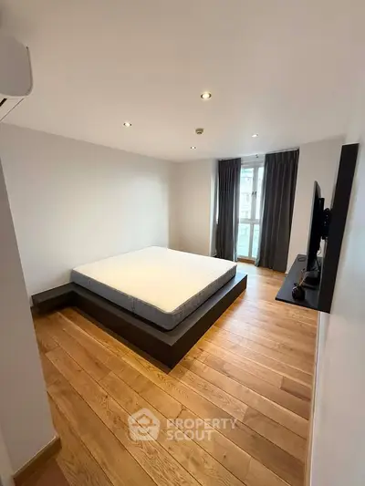 Modern minimalist bedroom with wooden flooring and large window