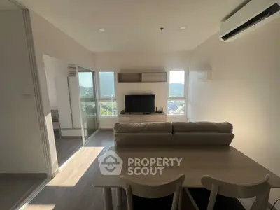 Modern living room with natural light, cozy sofa, and sleek dining area in a stylish apartment.