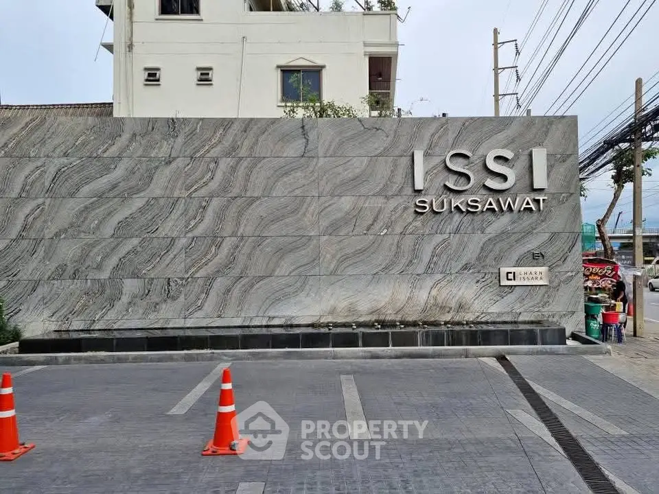 Modern condominium entrance with stylish stone facade and clear signage.