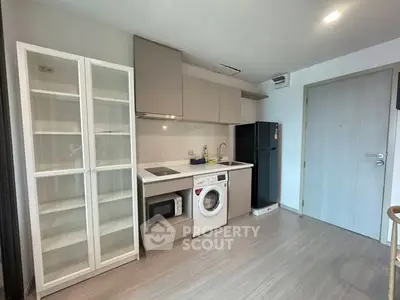 Modern kitchen with washing machine and sleek cabinetry in compact apartment