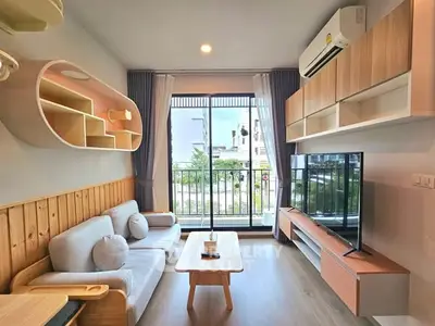 Modern living room with stylish furniture and balcony view, featuring a cozy sofa and wall-mounted TV.