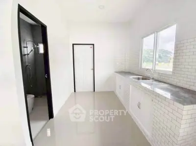 Modern kitchen with sleek countertops and adjacent bathroom in a bright, minimalist home.