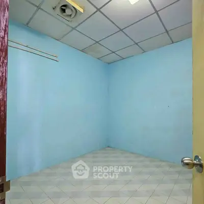 Empty room with blue walls and tiled floor, ideal for storage or small office space.
