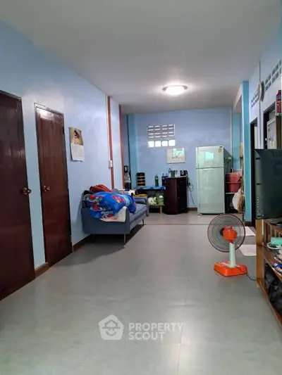 Cozy living room with blue walls, sofa, and kitchen area in open layout apartment.