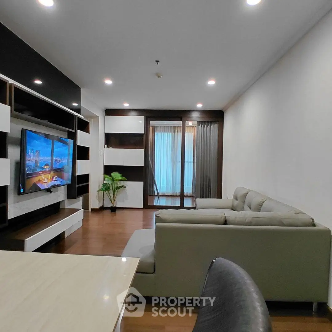 Modern living room with sleek furniture and large TV, featuring a cozy sofa and stylish decor.