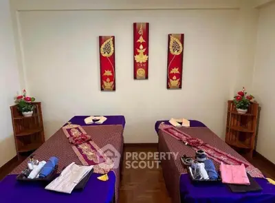 Elegant massage room with twin beds and decorative wall art in serene spa setting.