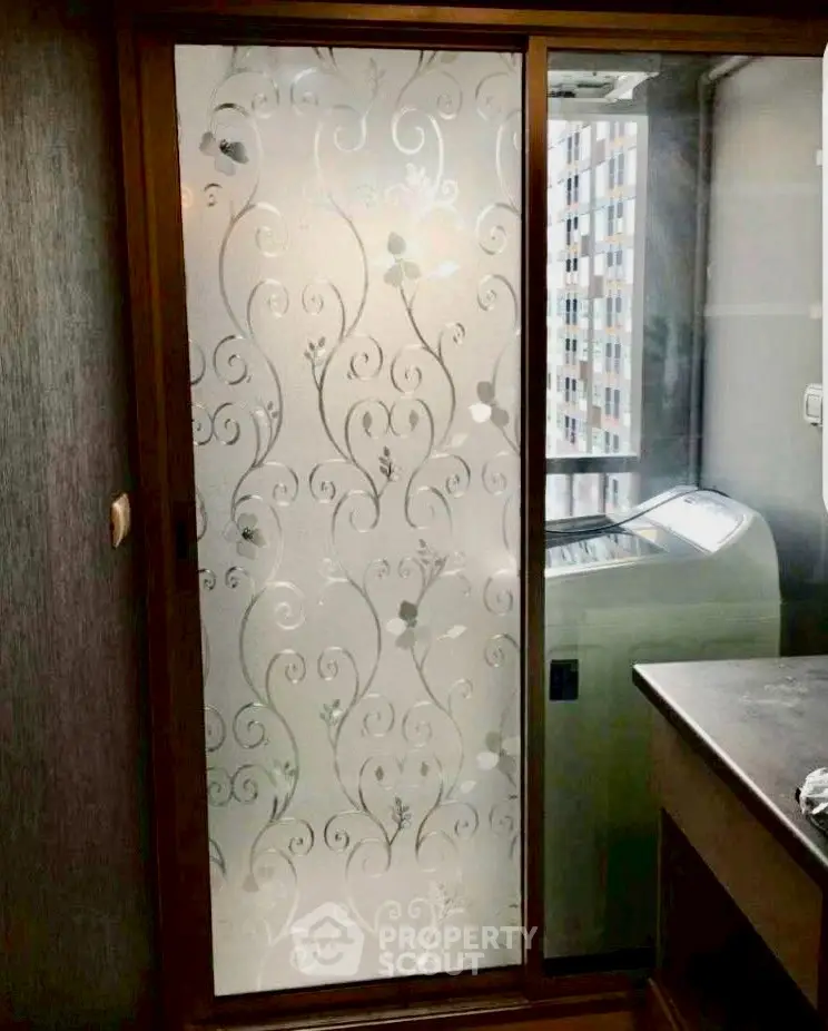 Stylish laundry area with frosted glass door and modern washing machine.