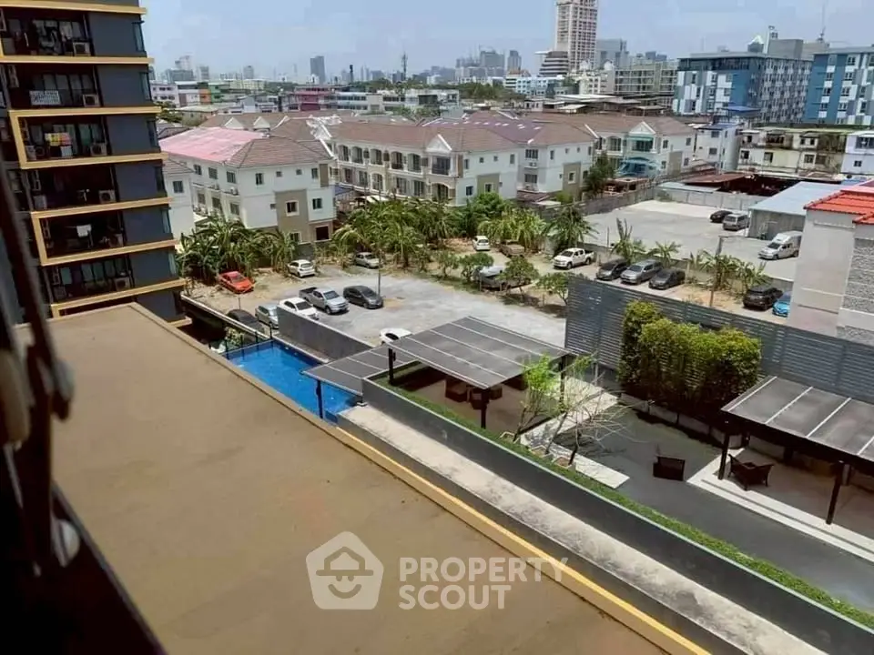 Stunning urban view from a high-rise balcony overlooking cityscape and pool area.