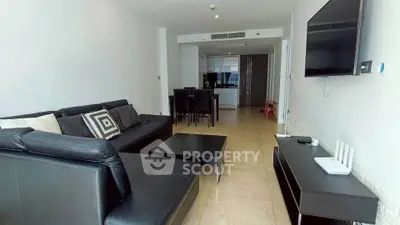 Spacious modern living room with sleek black furniture and open kitchen layout.
