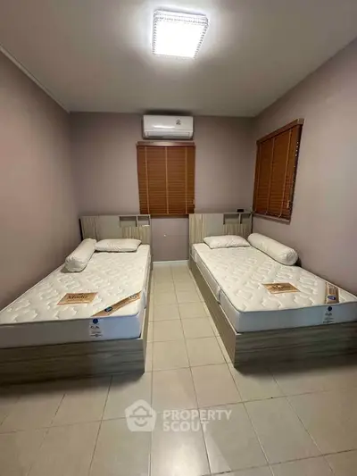 Cozy bedroom with twin beds and air conditioning, perfect for comfortable living.