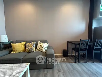 Modern living room with stylish sofa and dining area, featuring elegant decor and wooden flooring.