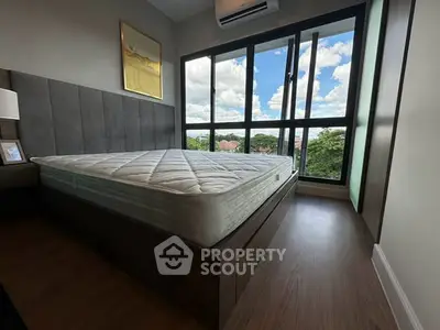 Modern bedroom with large windows offering a scenic view, featuring a stylish bed and wooden flooring.