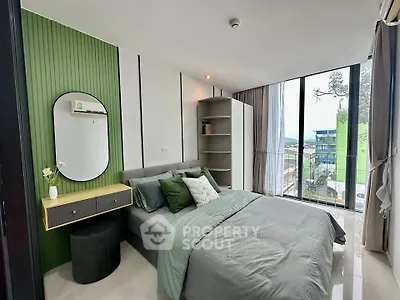 Modern bedroom with green accent wall and large windows offering city view