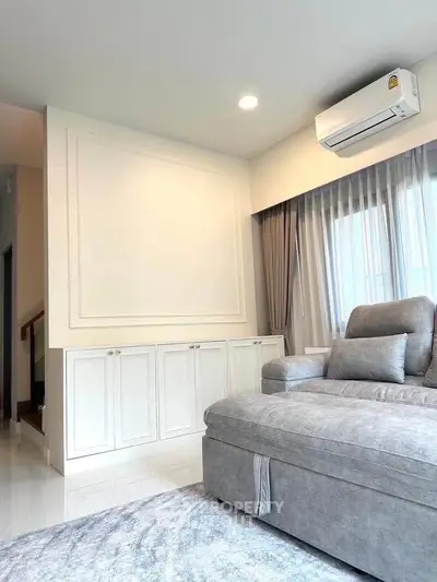 Modern living room with elegant sofa and air conditioning, featuring stylish decor and natural light.