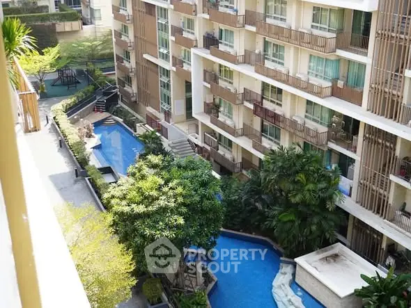 Luxurious apartment complex with stunning pool and lush greenery view.