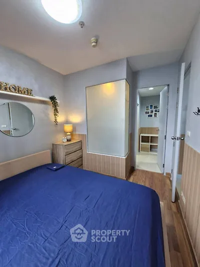 Cozy bedroom with modern decor and wooden flooring, featuring a stylish dresser and soft lighting.