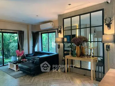 Elegant living room with black leather sofa, large mirror, and garden view.