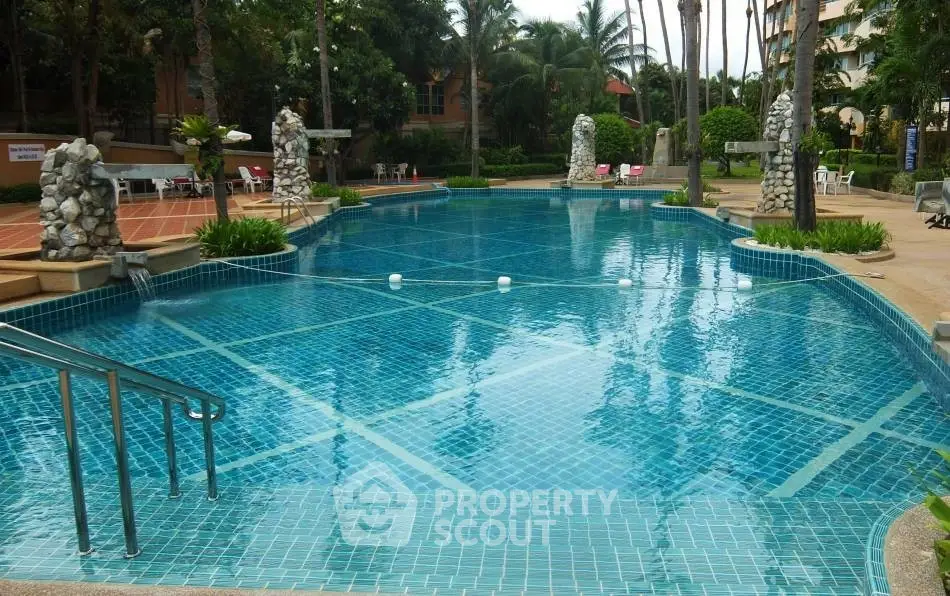 Luxurious outdoor pool with tropical landscaping and seating area in a serene residential complex.
