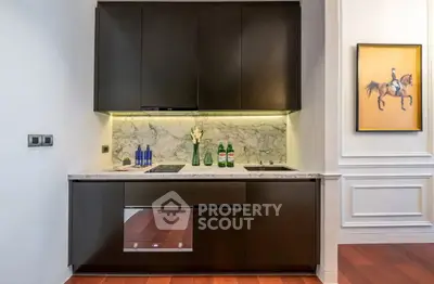 Modern kitchen with sleek cabinetry and marble backsplash, featuring built-in oven and elegant decor.