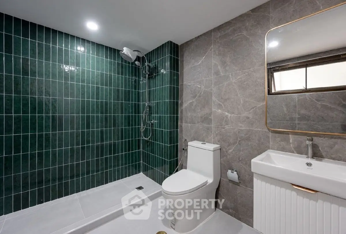 Modern bathroom with green tiled shower and sleek fixtures