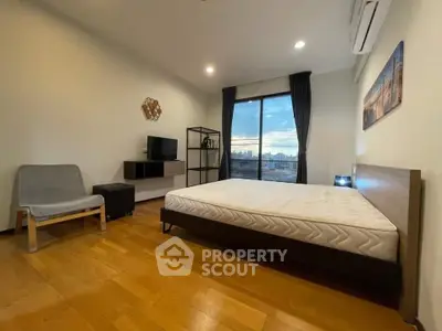 Spacious bedroom with city view, modern furnishings, and natural light.