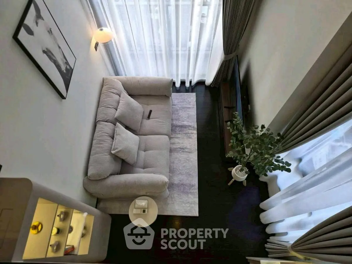 Modern living room with cozy sofa and elegant decor, featuring floor-to-ceiling windows and stylish lighting.