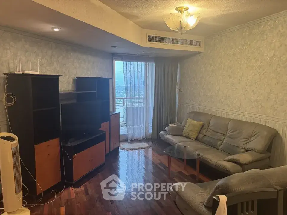 Cozy living room with leather sofas and wooden flooring, featuring a balcony view.