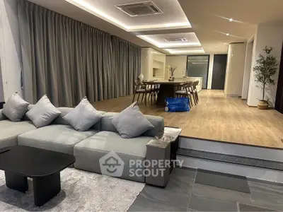 Spacious modern living room with open layout and elegant dining area, featuring stylish furniture and ambient lighting.