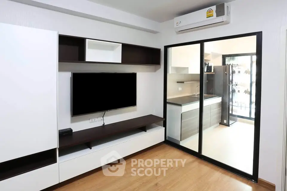 Modern living room with sleek TV unit and view into stylish kitchen