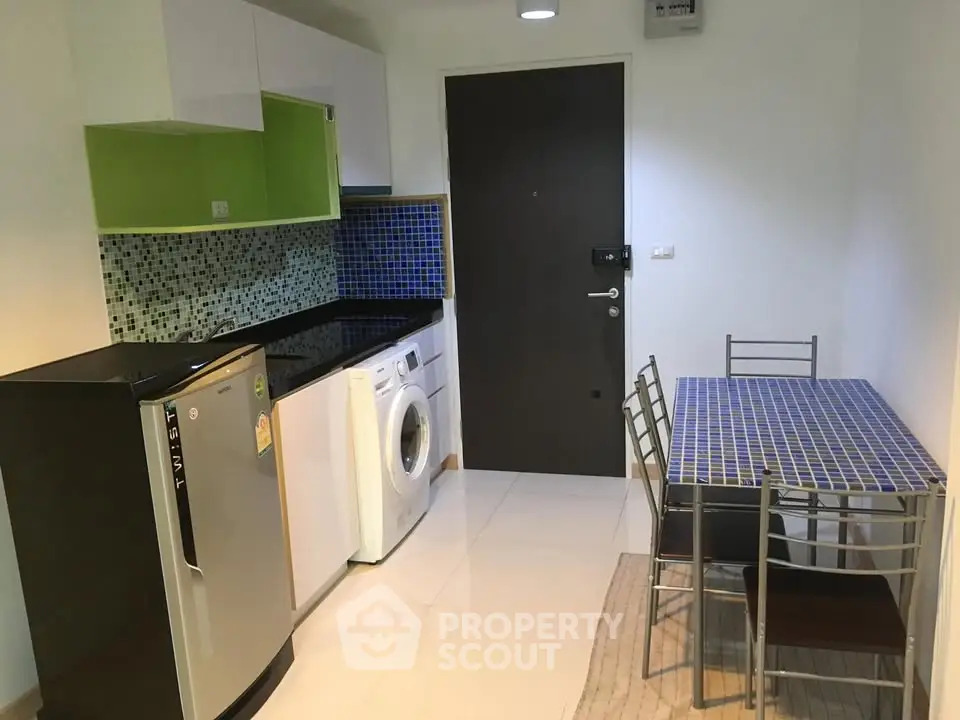 Modern compact kitchen with dining area, featuring washing machine and sleek appliances.