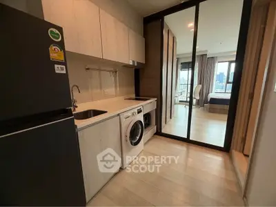Modern kitchen with washing machine and view into bedroom in stylish apartment