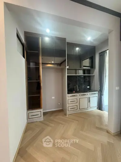 Modern kitchen with sleek cabinetry and herringbone wood flooring in a stylish apartment.