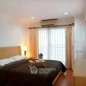 Cozy bedroom with natural light and modern furnishings in a stylish apartment.