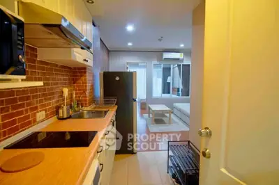 Cozy apartment kitchen with open layout leading to a modern living room, featuring sleek appliances and warm lighting.