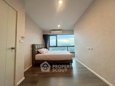 Spacious bedroom with city view and modern decor in high-rise apartment.