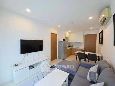 Modern living room with open kitchen, featuring sleek furniture and contemporary design.