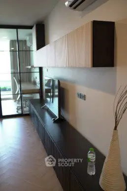 Modern living room with sleek TV unit and glass partition leading to a bright study area.