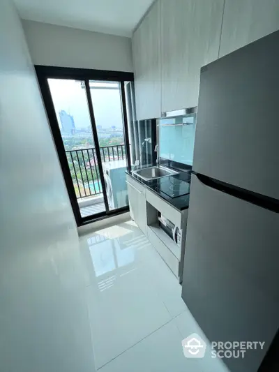 Sleek modern kitchen with high-gloss cabinetry and built-in appliances, complemented by a large window offering natural light and city views.