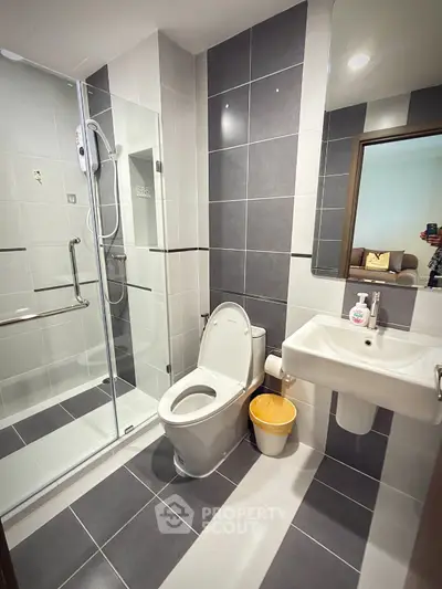 Modern bathroom with sleek design, featuring a glass shower enclosure and contemporary fixtures.