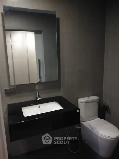 Modern bathroom with sleek fixtures and large mirror in a contemporary apartment.