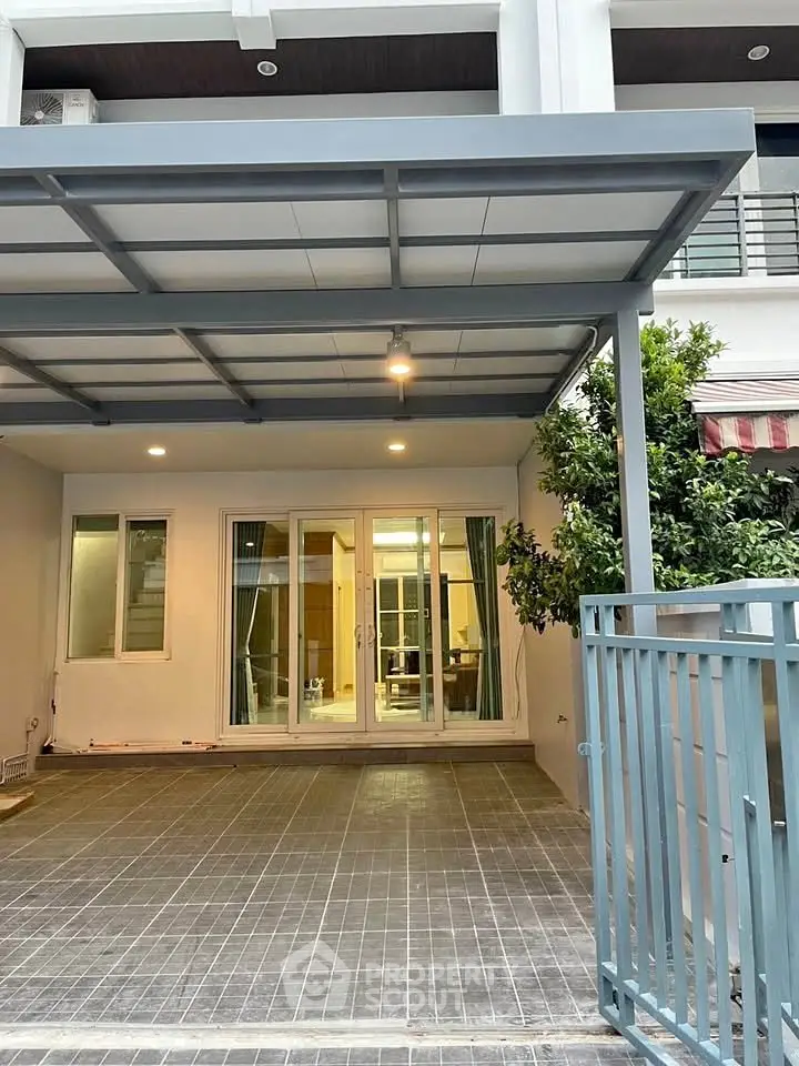 Modern townhouse exterior with covered parking and glass doors leading to the interior.