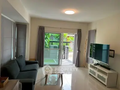 Spacious living room with modern decor and large windows overlooking greenery.