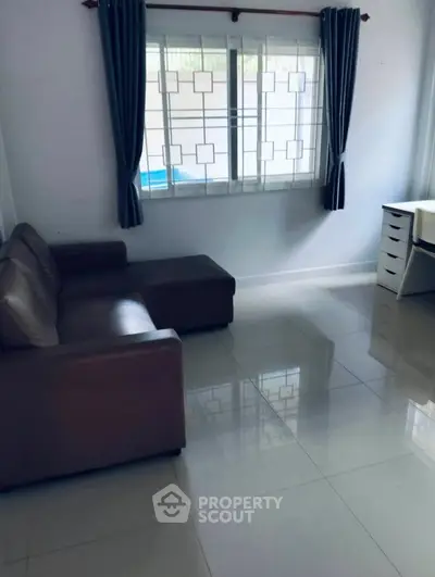 Spacious living room with modern sofa and large window, perfect for natural light.