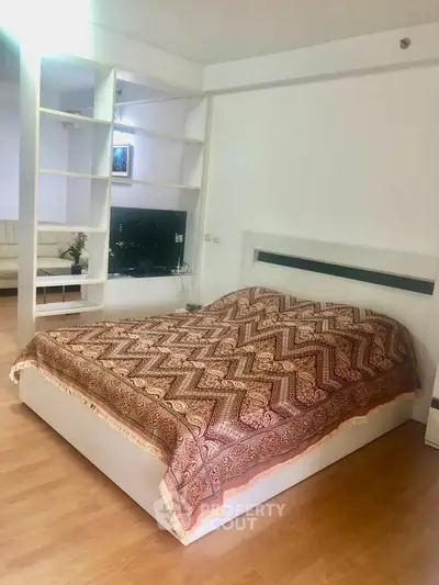 Spacious bedroom with modern decor and cozy ambiance, featuring a stylish bed and open shelving.