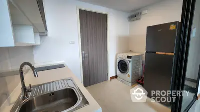 Modern kitchen with sleek appliances and washing machine in compact layout