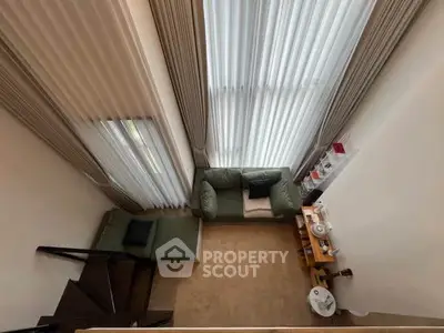 Spacious living room with high ceilings and modern decor, featuring large windows and cozy seating area.