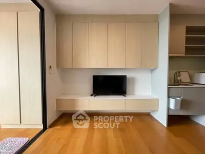 Modern minimalist living room with sleek wooden cabinetry and mounted TV.