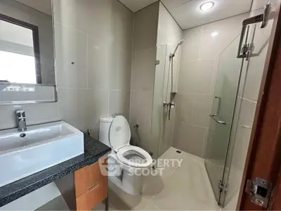 Modern bathroom with glass shower and sleek fixtures in contemporary apartment.